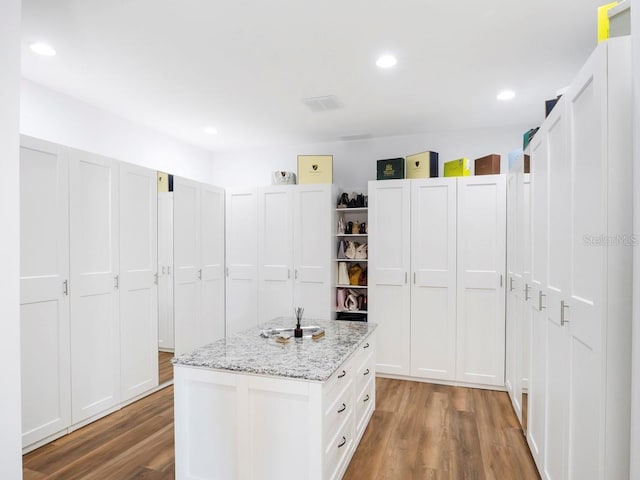 kitchen with wood-type flooring, white cabinetry, and a center island