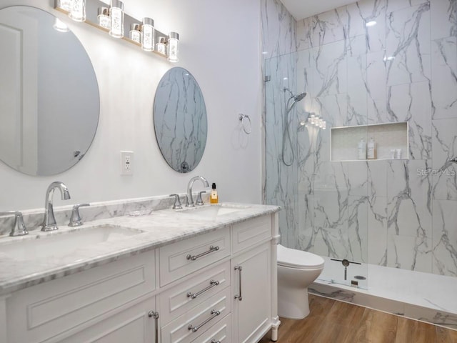 bathroom with hardwood / wood-style floors, tiled shower, vanity, and toilet