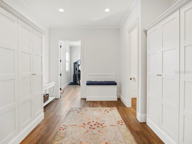 corridor with light hardwood / wood-style flooring and ornamental molding