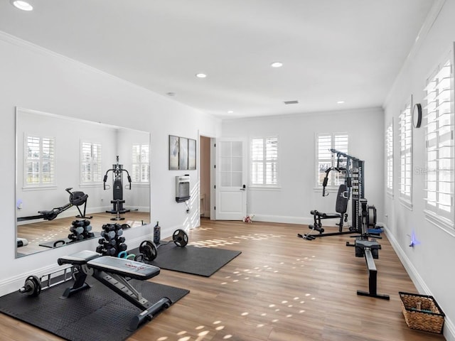 exercise room with light hardwood / wood-style flooring and ornamental molding