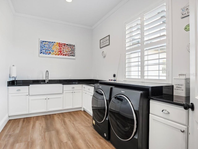 laundry room with light hardwood / wood-style floors, washing machine and dryer, cabinets, ornamental molding, and sink