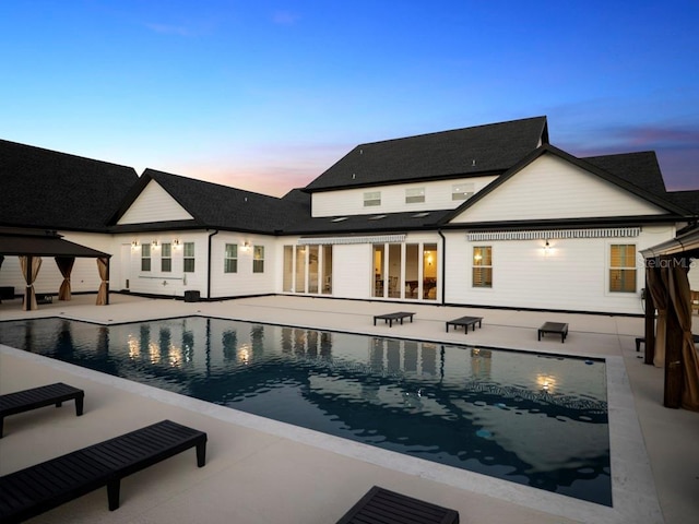 pool at dusk with a gazebo and a patio