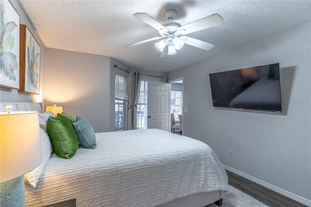 bedroom with a textured ceiling, ceiling fan, and dark wood-type flooring