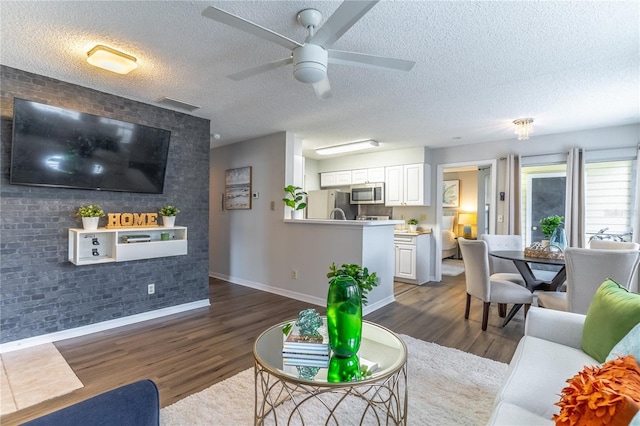 living room featuring ceiling fan, dark hardwood / wood-style floors, and a textured ceiling