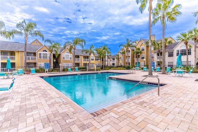 community pool featuring a residential view, fence, and a patio