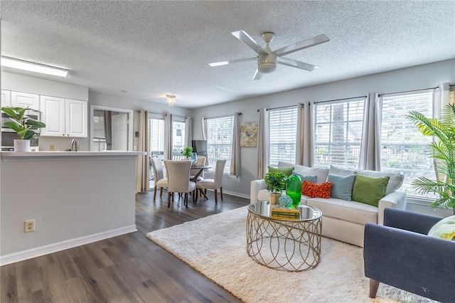living room with a textured ceiling, baseboards, a ceiling fan, and dark wood-style flooring