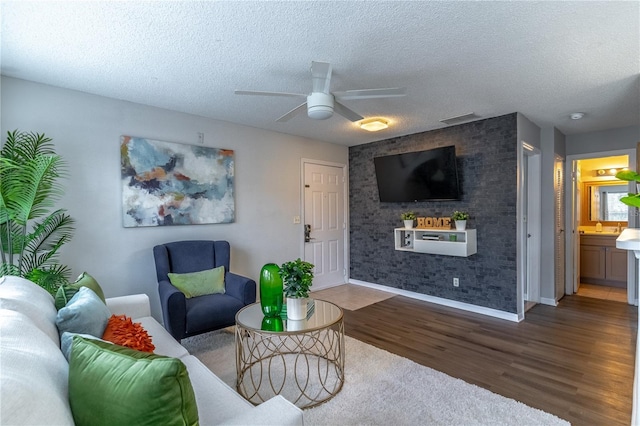 living room with wood finished floors, ceiling fan, a textured ceiling, and baseboards