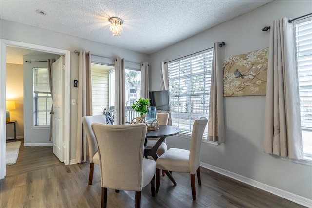 dining space with dark wood-style floors, a textured ceiling, and baseboards