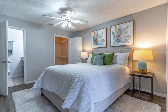 bedroom with baseboards, wood finished floors, a spacious closet, a closet, and a textured ceiling