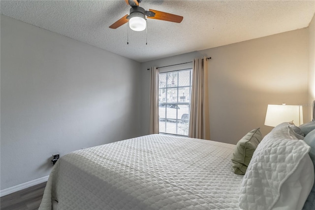 bedroom featuring wood finished floors, baseboards, a textured ceiling, and a ceiling fan