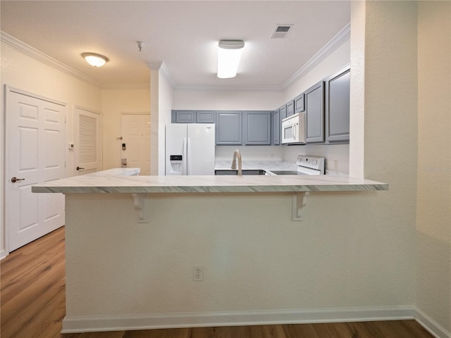 kitchen with a kitchen bar, white appliances, gray cabinets, and kitchen peninsula