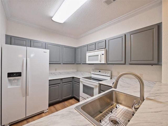 kitchen with crown molding, gray cabinets, sink, and white appliances