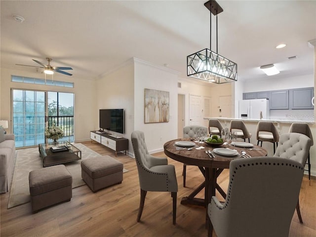 dining space with ceiling fan, crown molding, and light hardwood / wood-style flooring