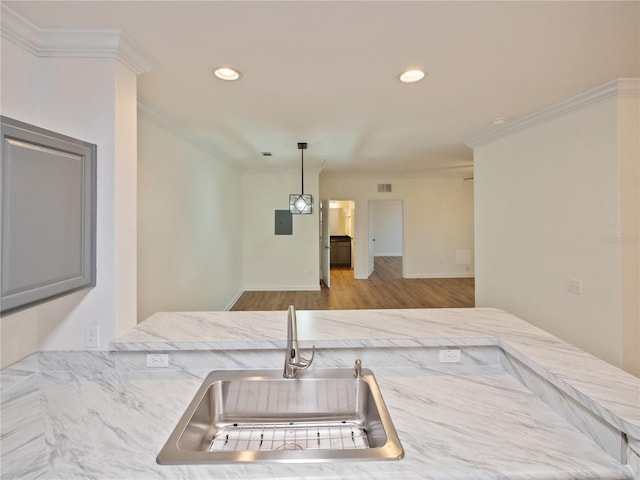 kitchen featuring hanging light fixtures, sink, crown molding, and light hardwood / wood-style floors