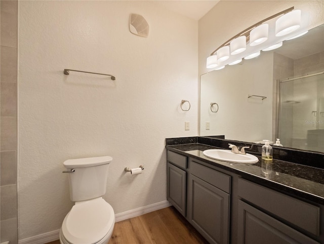 bathroom with an enclosed shower, vanity, wood-type flooring, and toilet