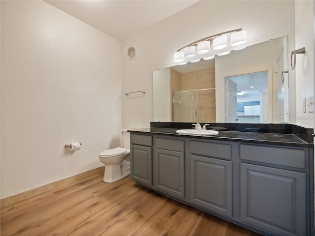 bathroom featuring toilet, a shower with shower door, hardwood / wood-style floors, and vanity