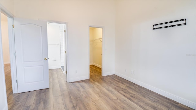 unfurnished bedroom featuring a spacious closet, a closet, and light hardwood / wood-style flooring