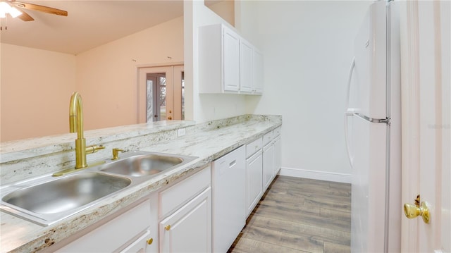 kitchen featuring white appliances, white cabinets, light hardwood / wood-style floors, sink, and vaulted ceiling