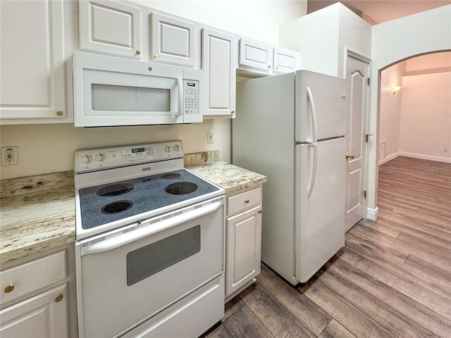 kitchen with hardwood / wood-style floors, white cabinets, light stone counters, and white appliances