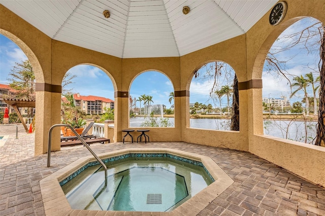 view of pool with an in ground hot tub, a patio area, and a water view