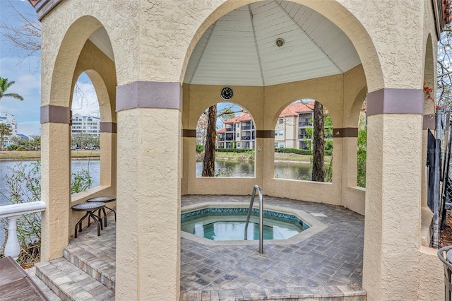 view of pool with a water view and a hot tub