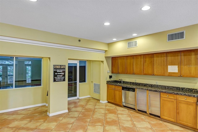 kitchen with brown cabinets, visible vents, and stainless steel dishwasher