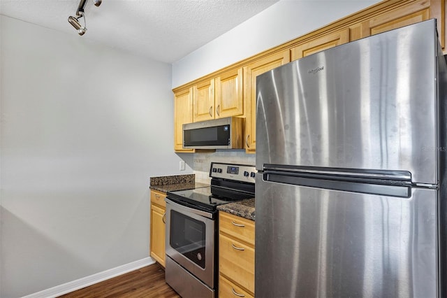 kitchen featuring a textured ceiling, baseboards, appliances with stainless steel finishes, backsplash, and dark wood-style floors