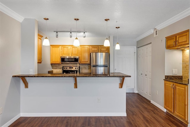 kitchen featuring dark stone counters, stainless steel appliances, a peninsula, and dark wood-style floors