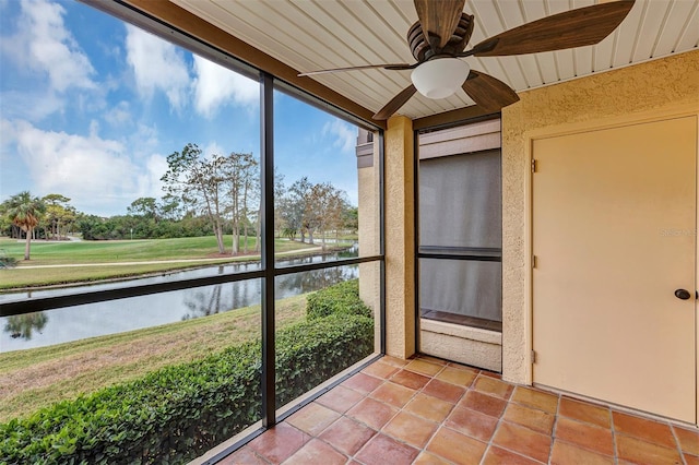 unfurnished sunroom featuring ceiling fan and a water view