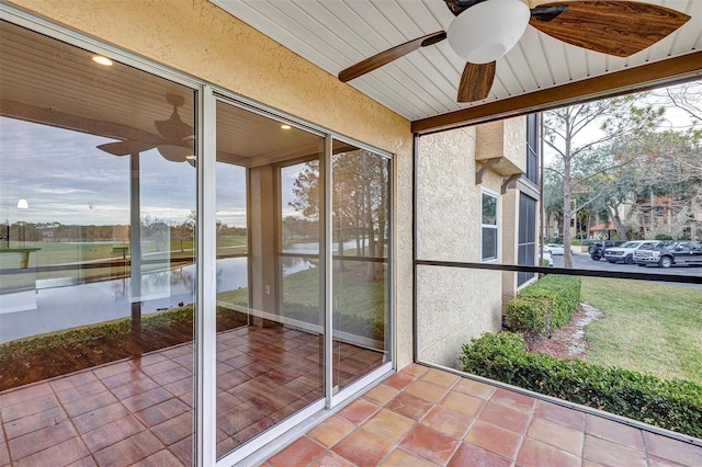 unfurnished sunroom with a water view and ceiling fan