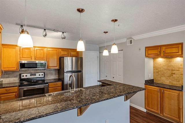 kitchen with stainless steel appliances, dark wood-type flooring, a sink, visible vents, and pendant lighting