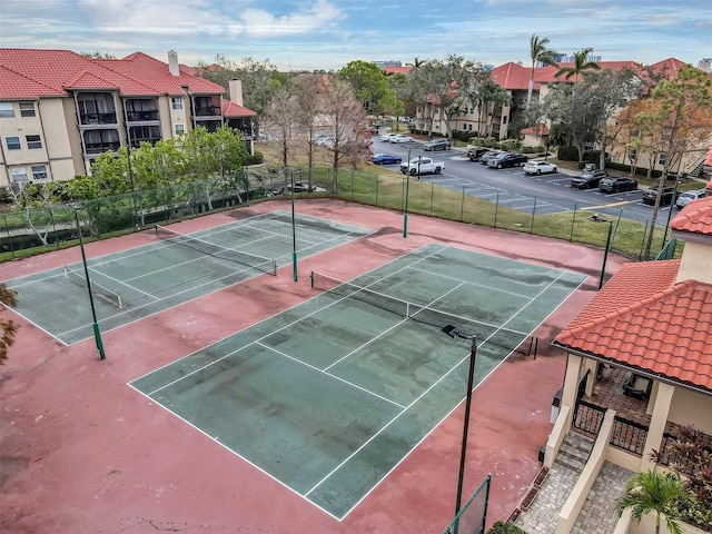 view of tennis court with a residential view and fence