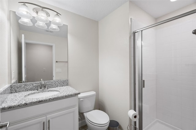 bathroom with toilet, vanity, a textured ceiling, and a shower with shower door