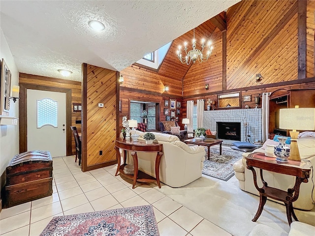 living room with light tile patterned floors, a brick fireplace, wooden walls, and a textured ceiling