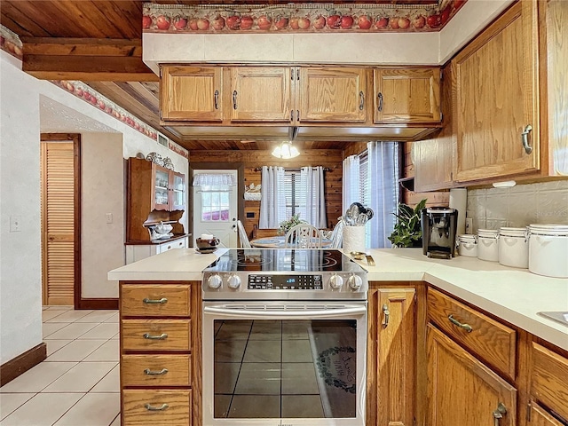 kitchen with kitchen peninsula, stainless steel electric range oven, backsplash, and light tile patterned flooring