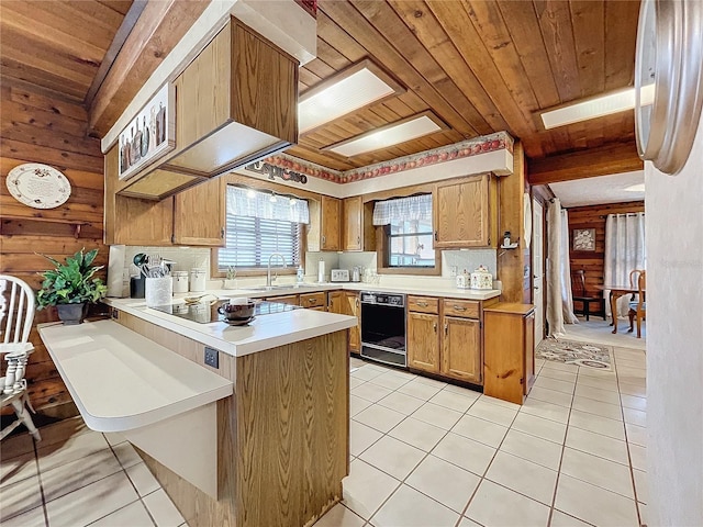 kitchen with wood walls, black appliances, and kitchen peninsula