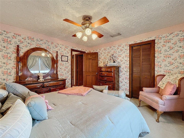 carpeted bedroom with a textured ceiling, ceiling fan, and a closet