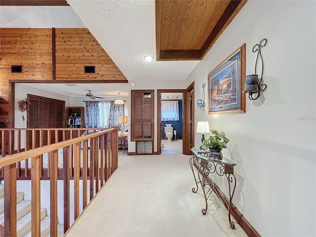 hall with carpet floors, wooden ceiling, and vaulted ceiling