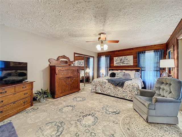 bedroom featuring ceiling fan, a textured ceiling, a closet, and wood walls