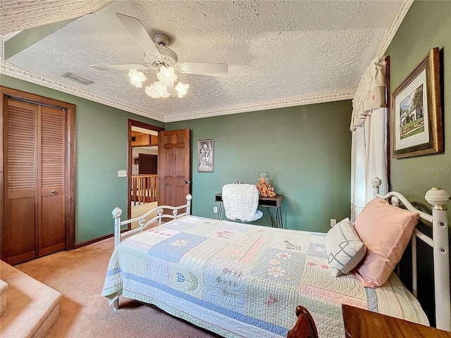 bedroom with a textured ceiling, a closet, ornamental molding, ceiling fan, and light colored carpet