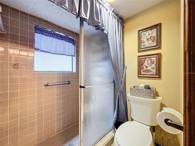 bathroom featuring a shower with shower door and toilet