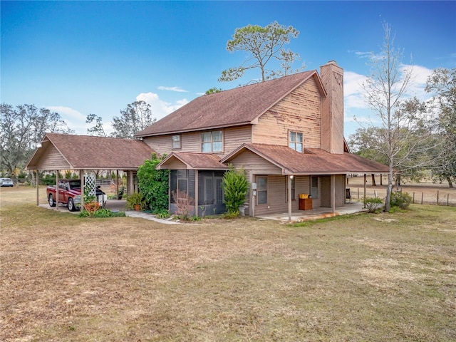 back of property featuring a patio area, a sunroom, and a lawn