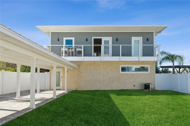 back of property with a patio area, a lawn, cooling unit, and a balcony