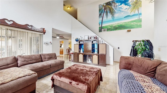 living room with ceiling fan, a high ceiling, and light tile patterned floors