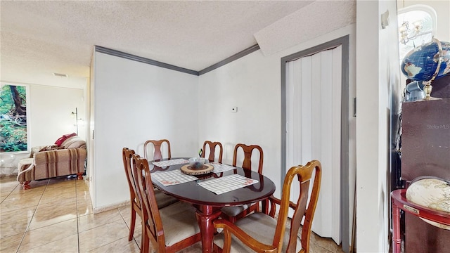 dining room featuring light tile patterned floors, a textured ceiling, and ornamental molding