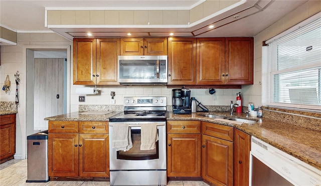 kitchen with sink, stone countertops, stainless steel appliances, and tasteful backsplash