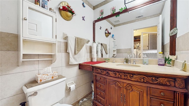 bathroom with toilet, tile walls, and vanity