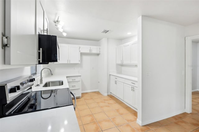 kitchen with light tile patterned flooring, white cabinets, electric range, and sink