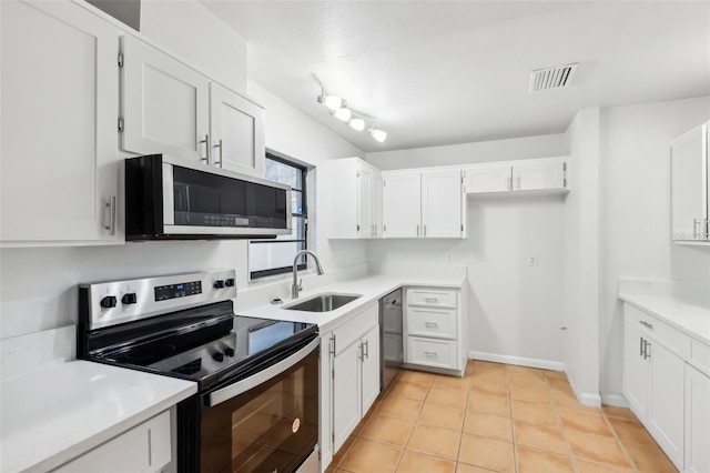 kitchen with white cabinets, appliances with stainless steel finishes, sink, and light tile patterned flooring