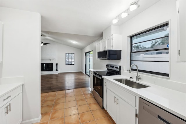 kitchen featuring vaulted ceiling, sink, light tile patterned floors, stainless steel appliances, and white cabinets